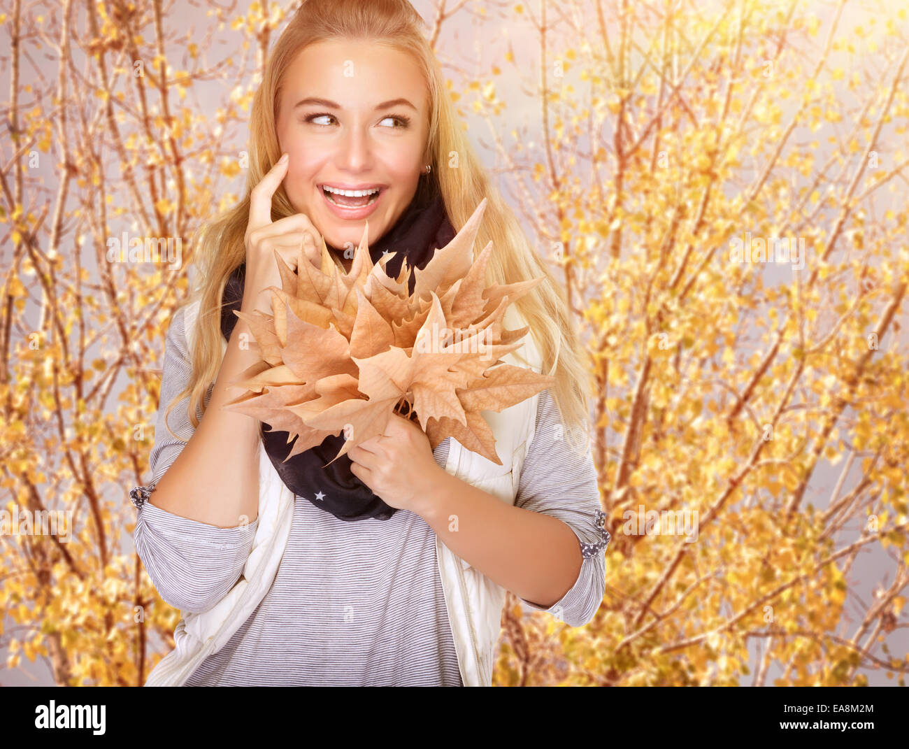 Portrait of cute happy girl with dry maple leaves bouquet in the park, spending time outdoors, enjoying autumn concept Stock Photo