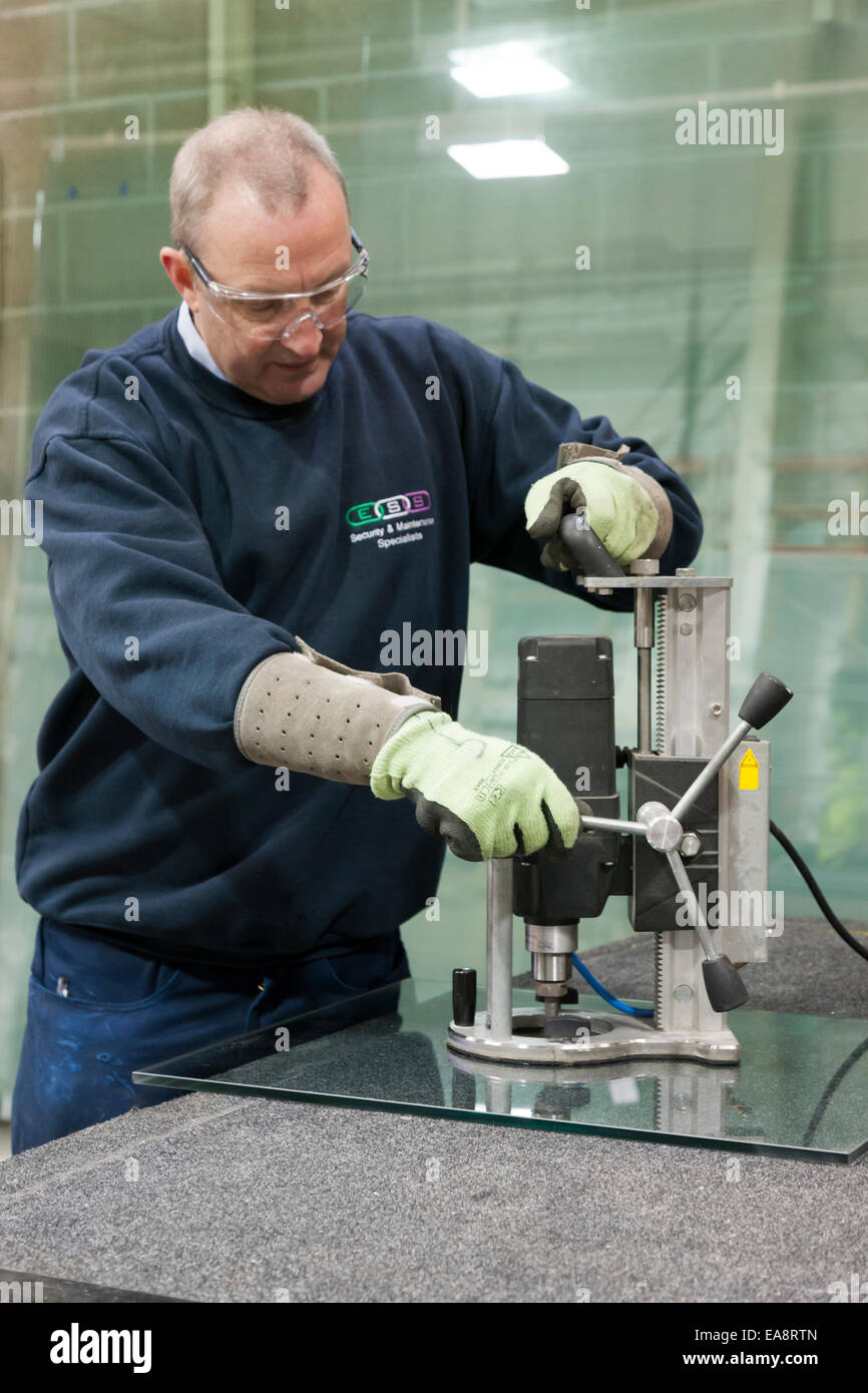A workman operating a glass cutting and drilling machine Stock Photo ...