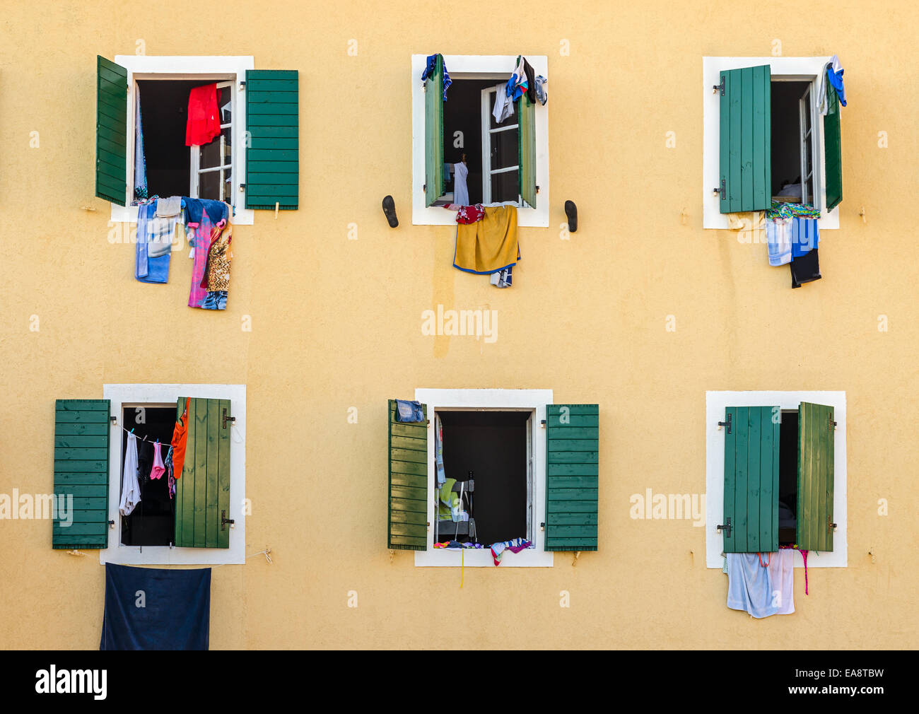 Windows with laundry hanging on the open wooden shutters Stock Photo