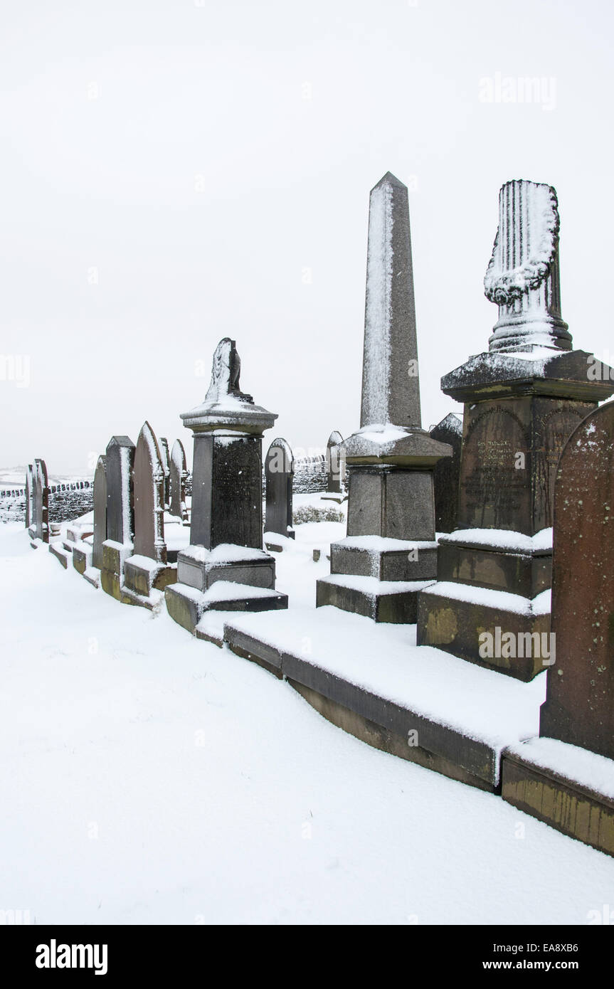 Snow covered gravestones and monuments in a hillside graveyard in Charlesworth near Glossop, Derbyshire. Stock Photo