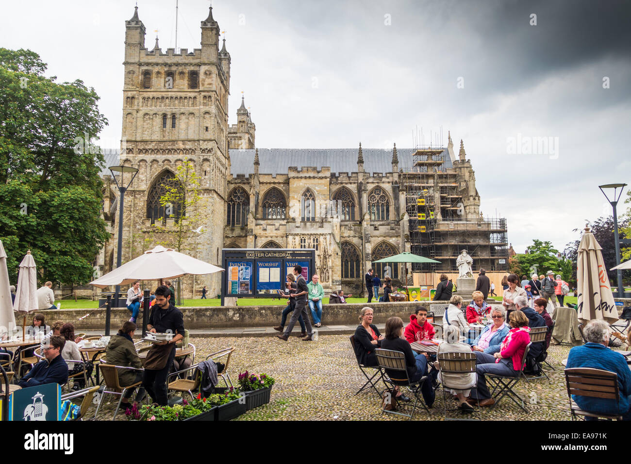 Exeter Cathedral and Cathedral Close with people sitting and eating on the cobbled close in front of the Cathedral. Founded 1050 Stock Photo