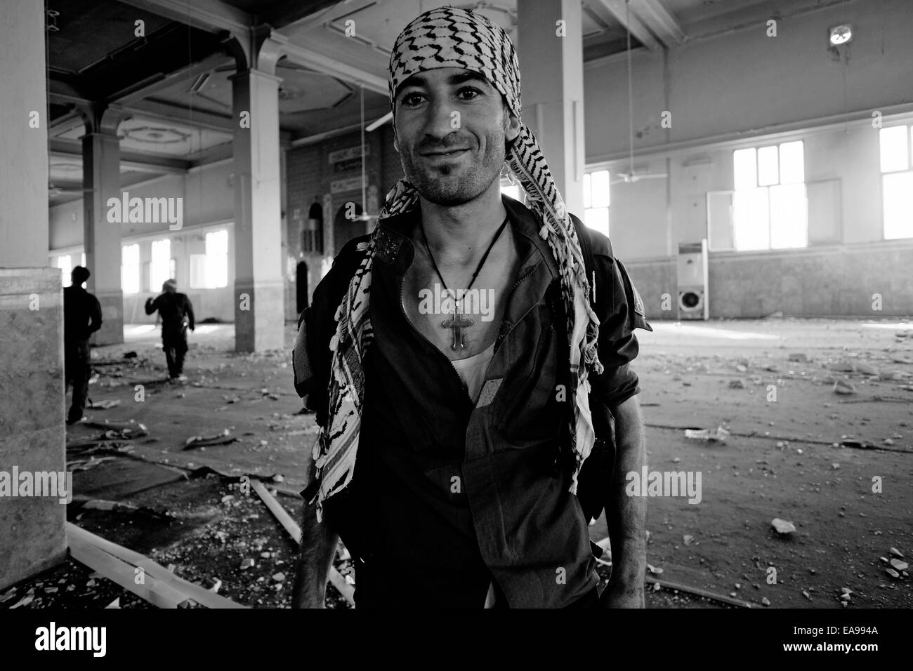 A member of the Syriac Security Office commonly known as the Sutoro or the Sutoro Police an Assyrian, Christian police force wearing a cross necklace posing to the camera inside a Sufi shrine of Sheikh Khaznawi destroyed by ISIS or ISIL in Tel Marouf or Tall Maruf village in Al Hasakah or Hassakeh district in north eastern Syria Stock Photo