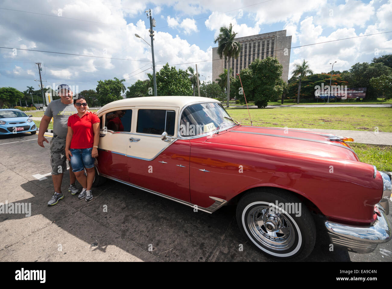 A driver and tour guide wait by their classic 1955 Pontiac at Revolution square Plaza de la Revolución in downtown Havana Cuba Stock Photo