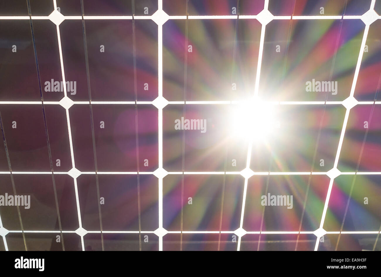 Solar panels wit sun burst flare. Solar panel seen from behind, underneath. Solar cells on clear glass with sun shining through. Stock Photo