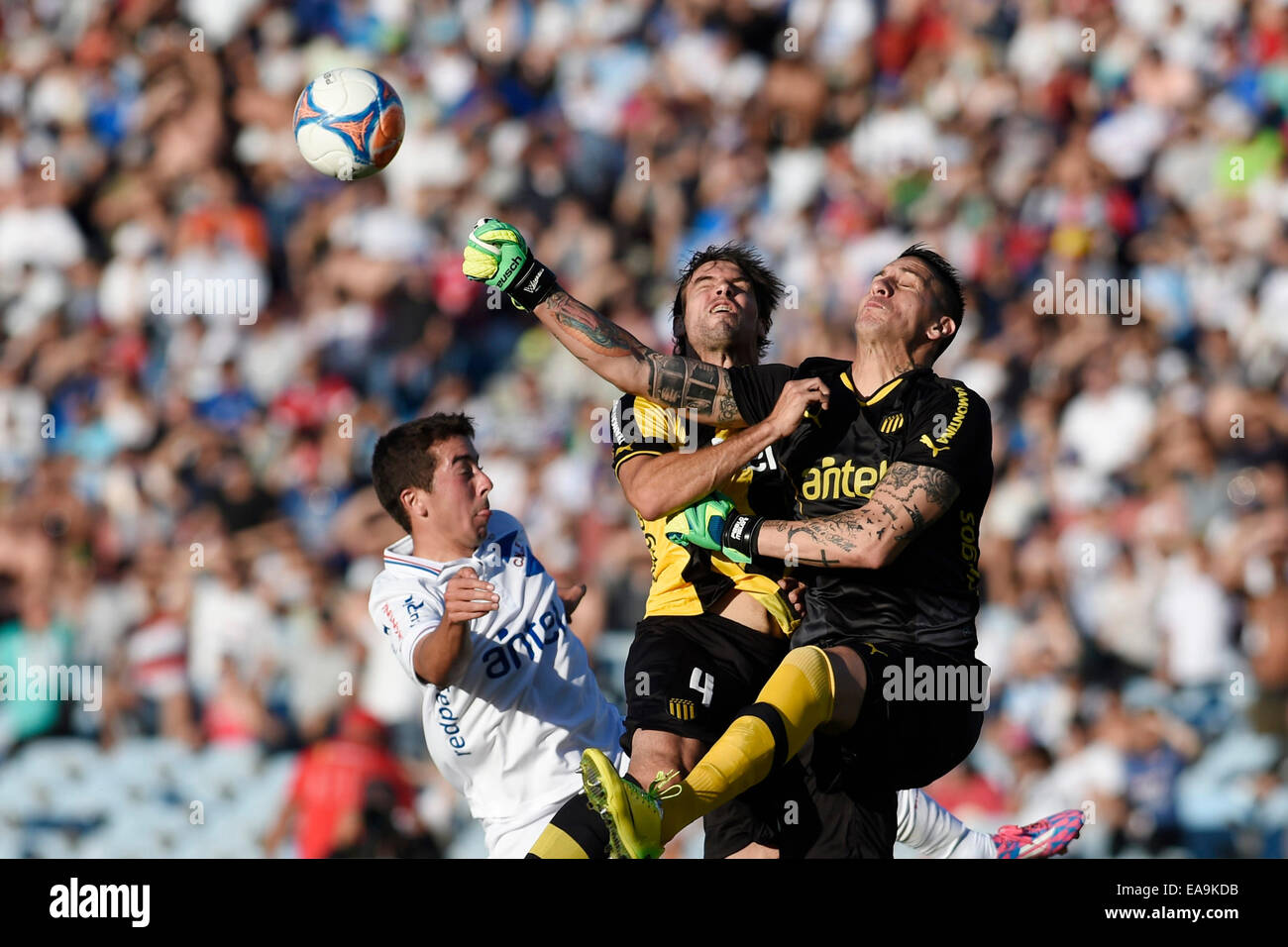 Montevideo, Uruguay. 9th Nov, 2014. Carlos de Pena (L) of Nacional vies for the ball with goalkeeper Pablo Migliore (R) and Gonzalo Viera of Penarol during their match in the Centenario Stadium, in Montevideo, capital of Uruguay, on Nov. 9, 2014. Credit:  Nicolas Celaya/Xinhua/Alamy Live News Stock Photo