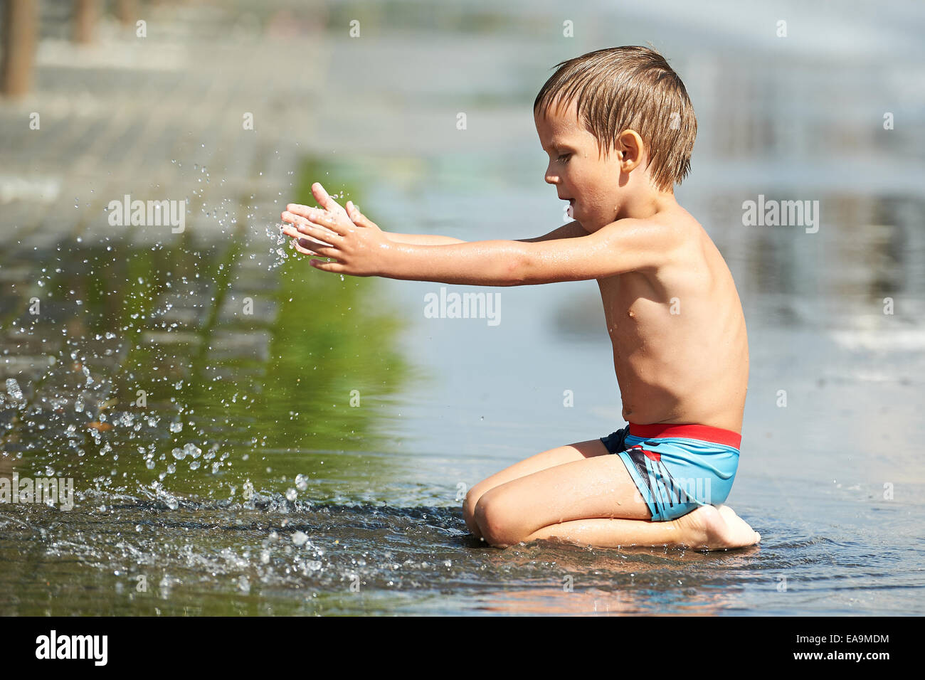 Little boy playing with water in a puddle in the park Stock Photo