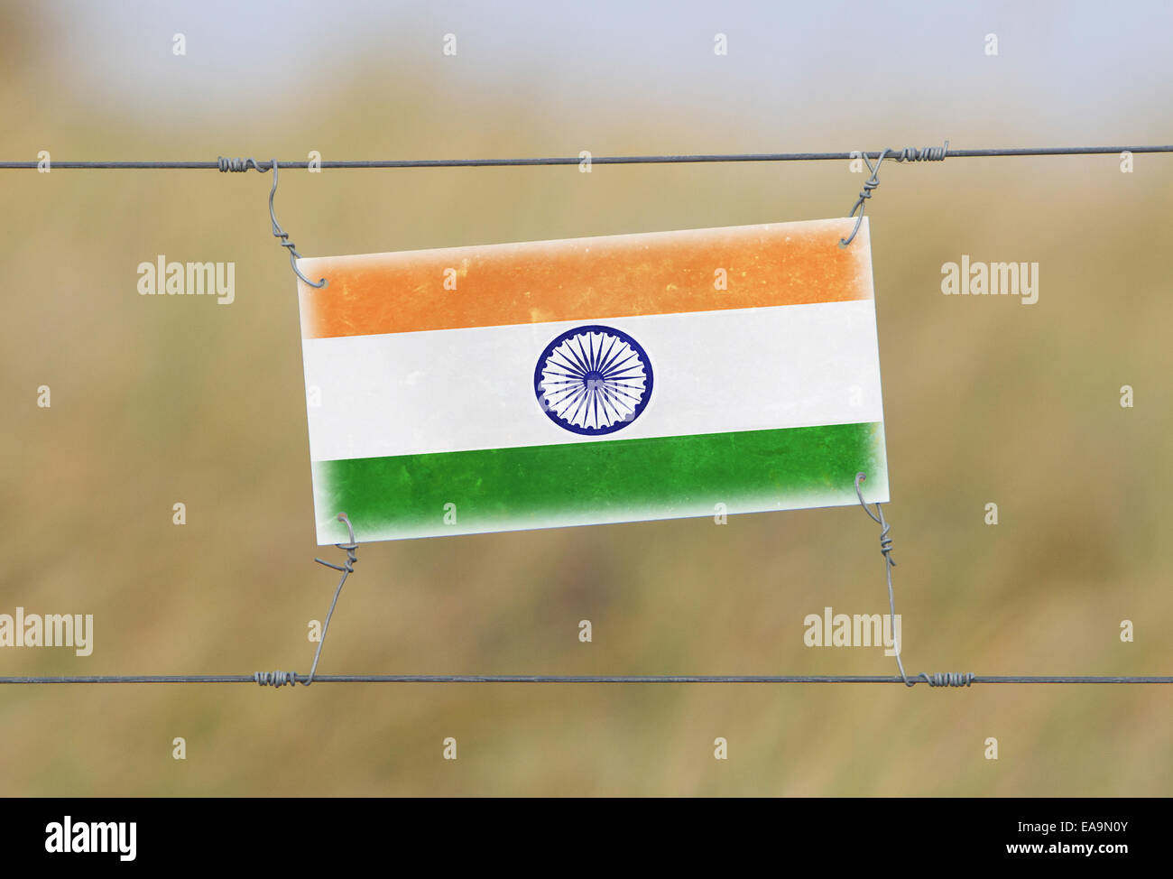 Border fence - Old plastic sign with a flag - India Stock Photo