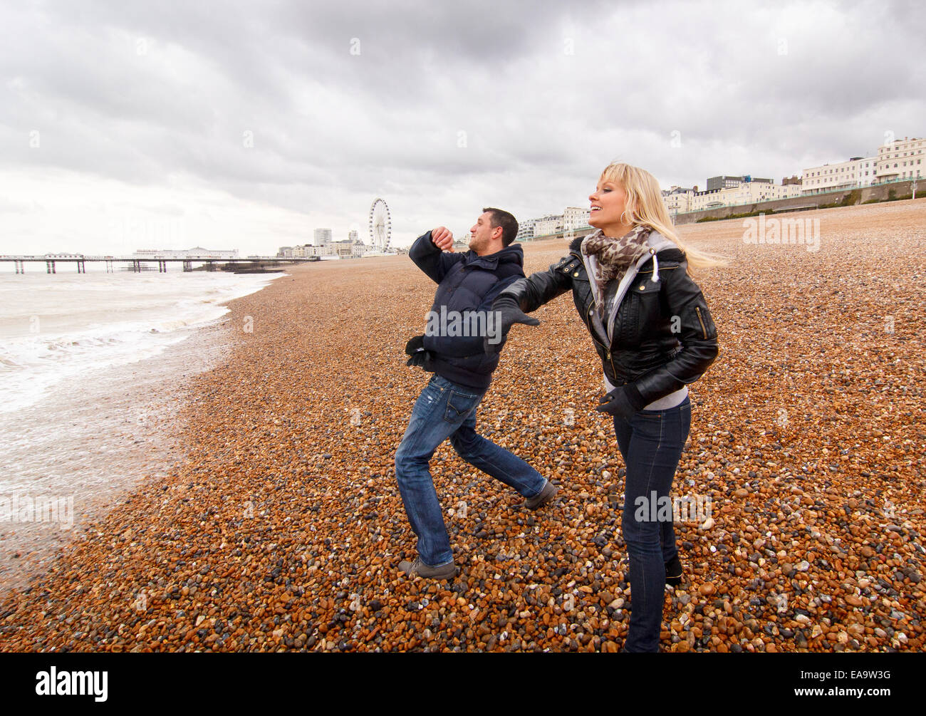 A couple enjoying a day out at the British seaside in Brighton in warm winter clothing Stock Photo