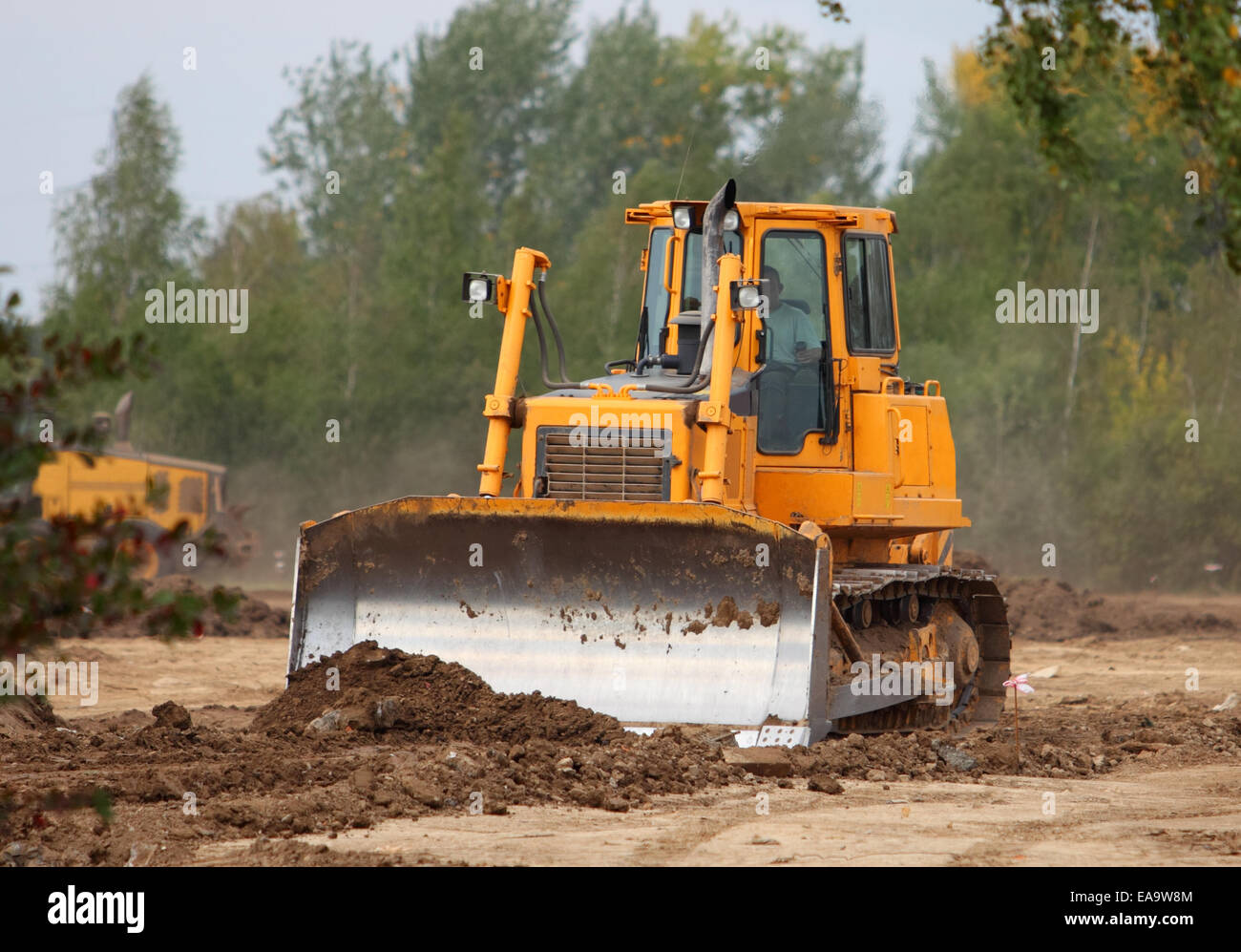 Industrial backhoe, bulldozer moving earth and sand in sandpit or quarry Stock Photo