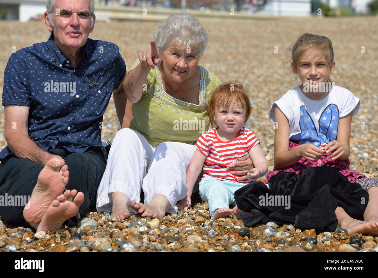 Grandparents sitting on Eastbourne beach with their grandchildren Stock Photo