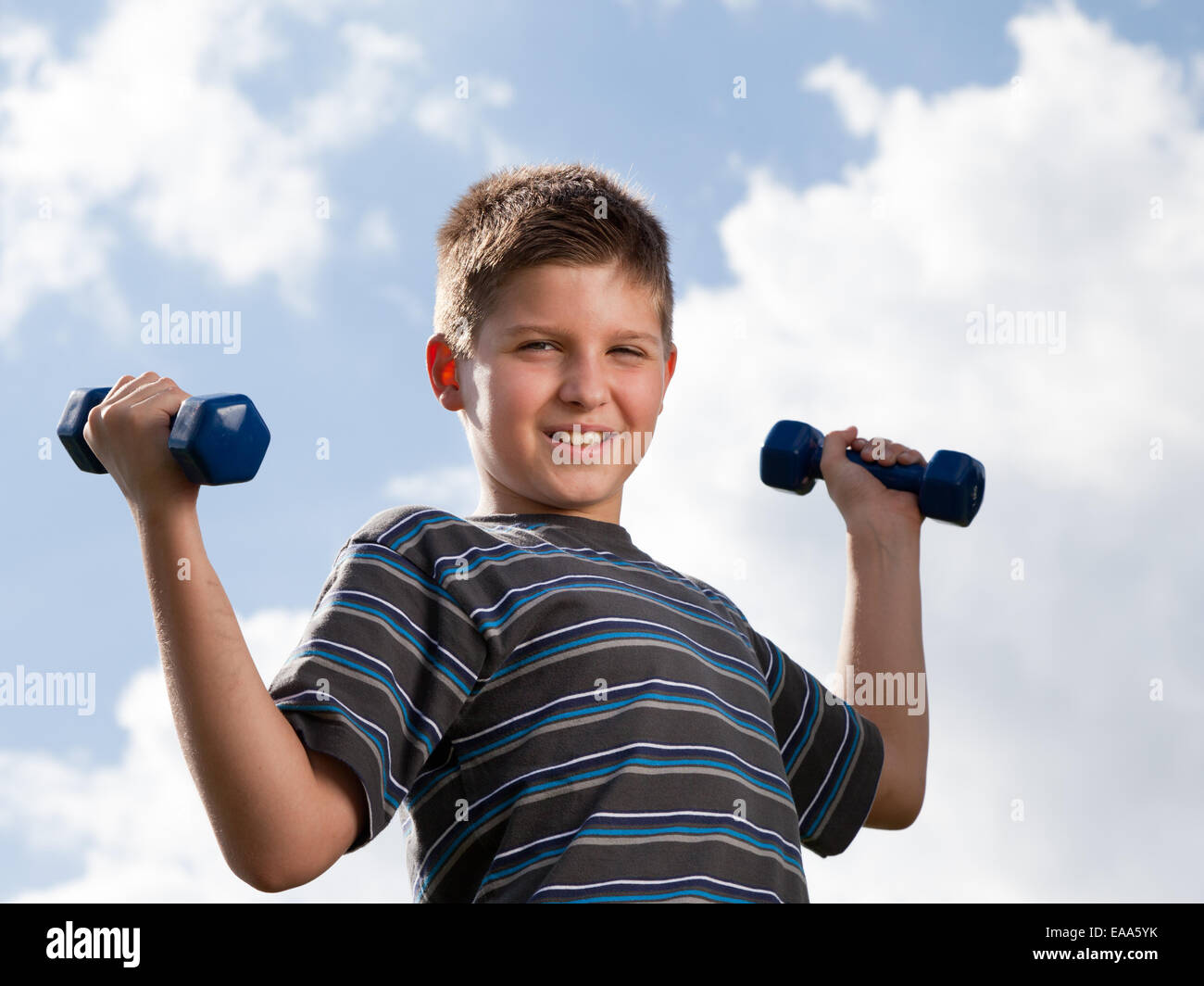 Happy boy lifting dumbbells outdoors Stock Photo