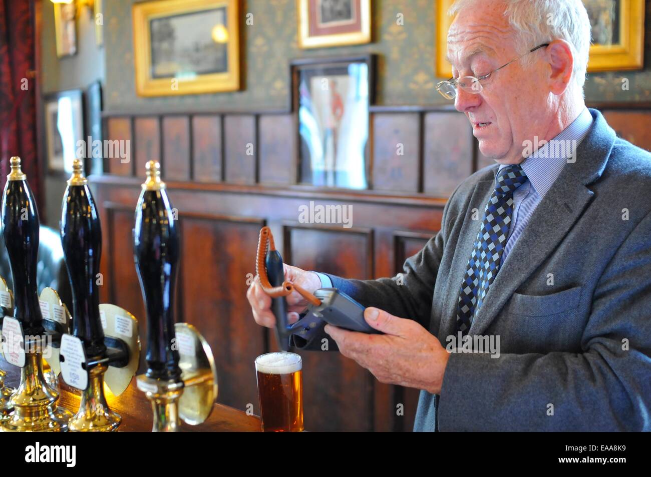Man from Cask Marque checking the temperature of a glass of beer at The Victoria pub, near Paddington, London Stock Photo