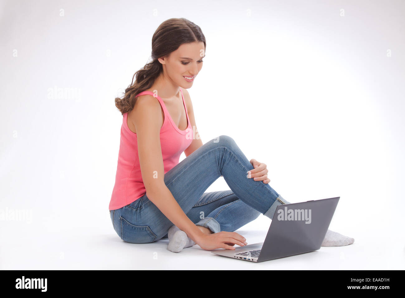 Beautiful young woman in a red vest and blue jeans with laptop Stock ...