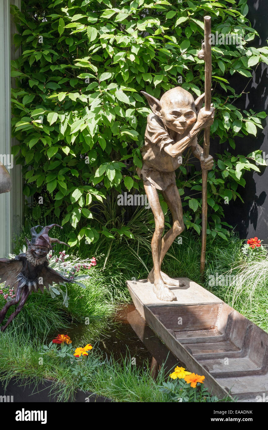 Chelsea Flower Show 2014. Metal gremlin sculpture in a punt with a hornbeam tree (Carpinus betulus) behind Stock Photo