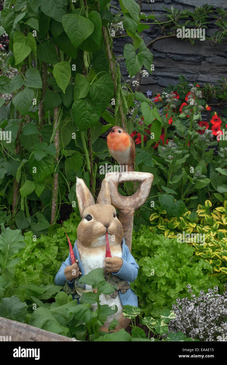 Chelsea Flower Show 2014. Peter Rabbit and a robin perch on top of an antique fork handle in amongst a vegetable plot Stock Photo