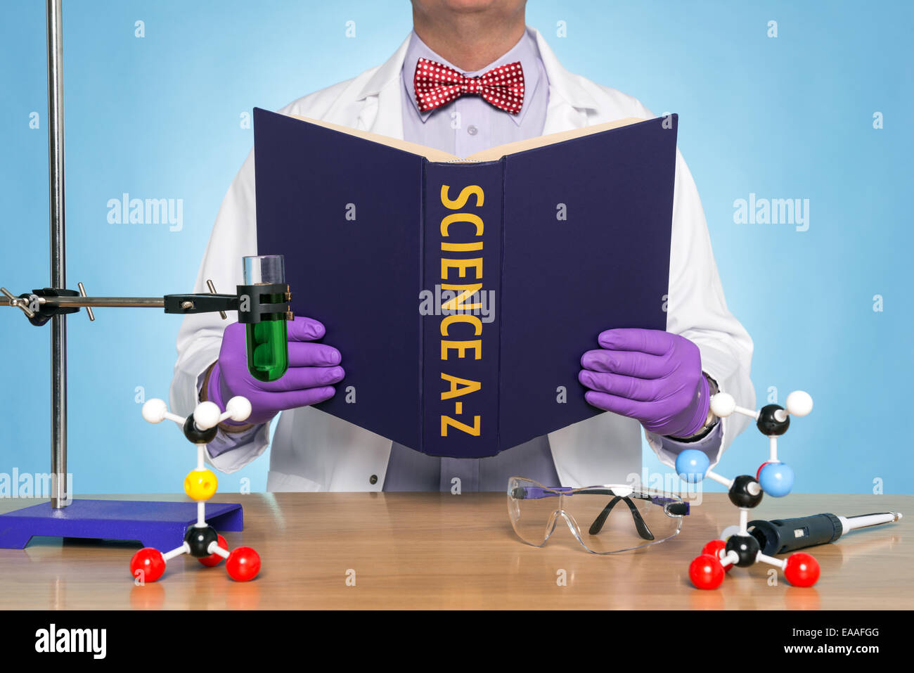 A scientist sat at a desk reading a SCIENCE A-Z book Stock Photo