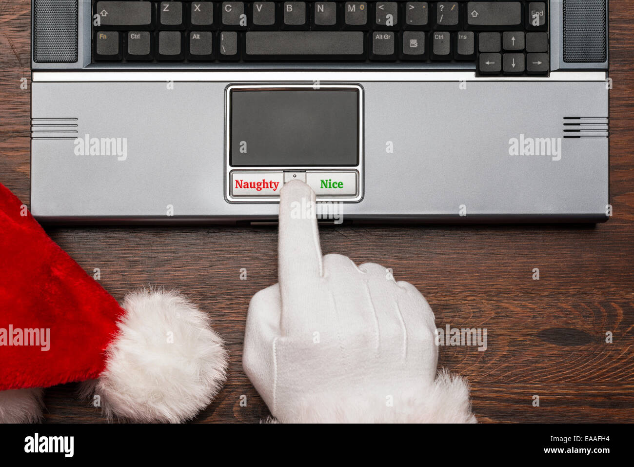 Father Christmas or Santa checking his list on a computer to select if a boy or girl is either Naughty or Nice. Stock Photo