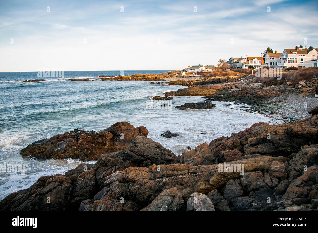 Golden sunlit land & homes on rocky coastal inlet Stock Photo Alamy