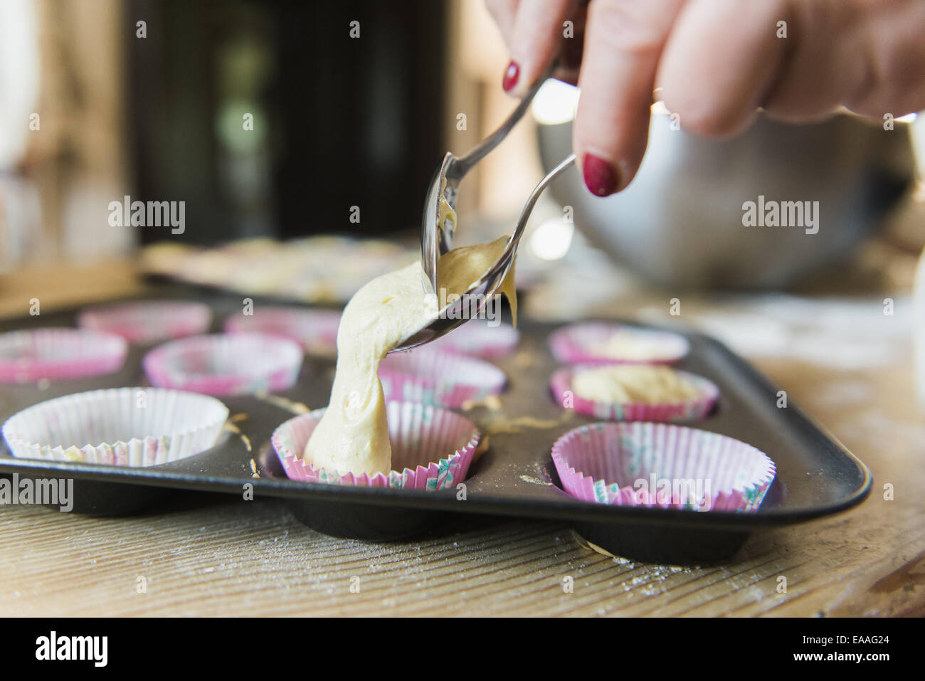 A woman at a kitchen table baking fairy cakes. Stock Photo