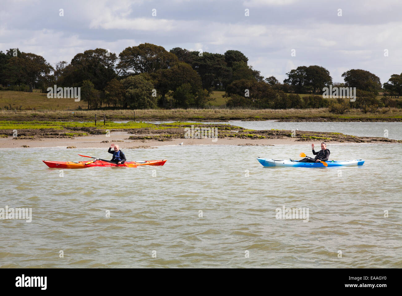 Canoeists on a river waving at a passing boat Stock Photo