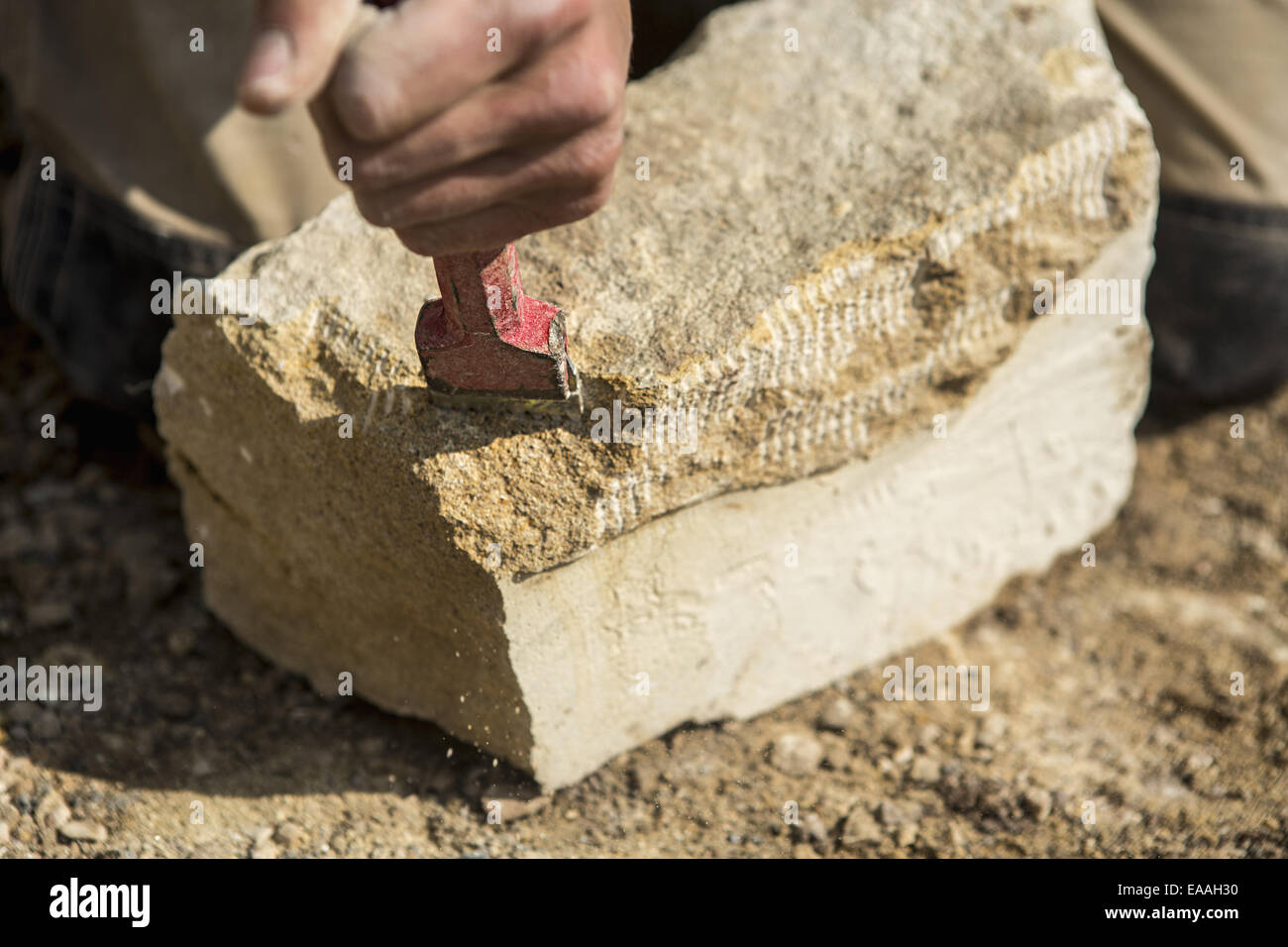 Construction worker holding a chisel, working on a stone Stock Photo