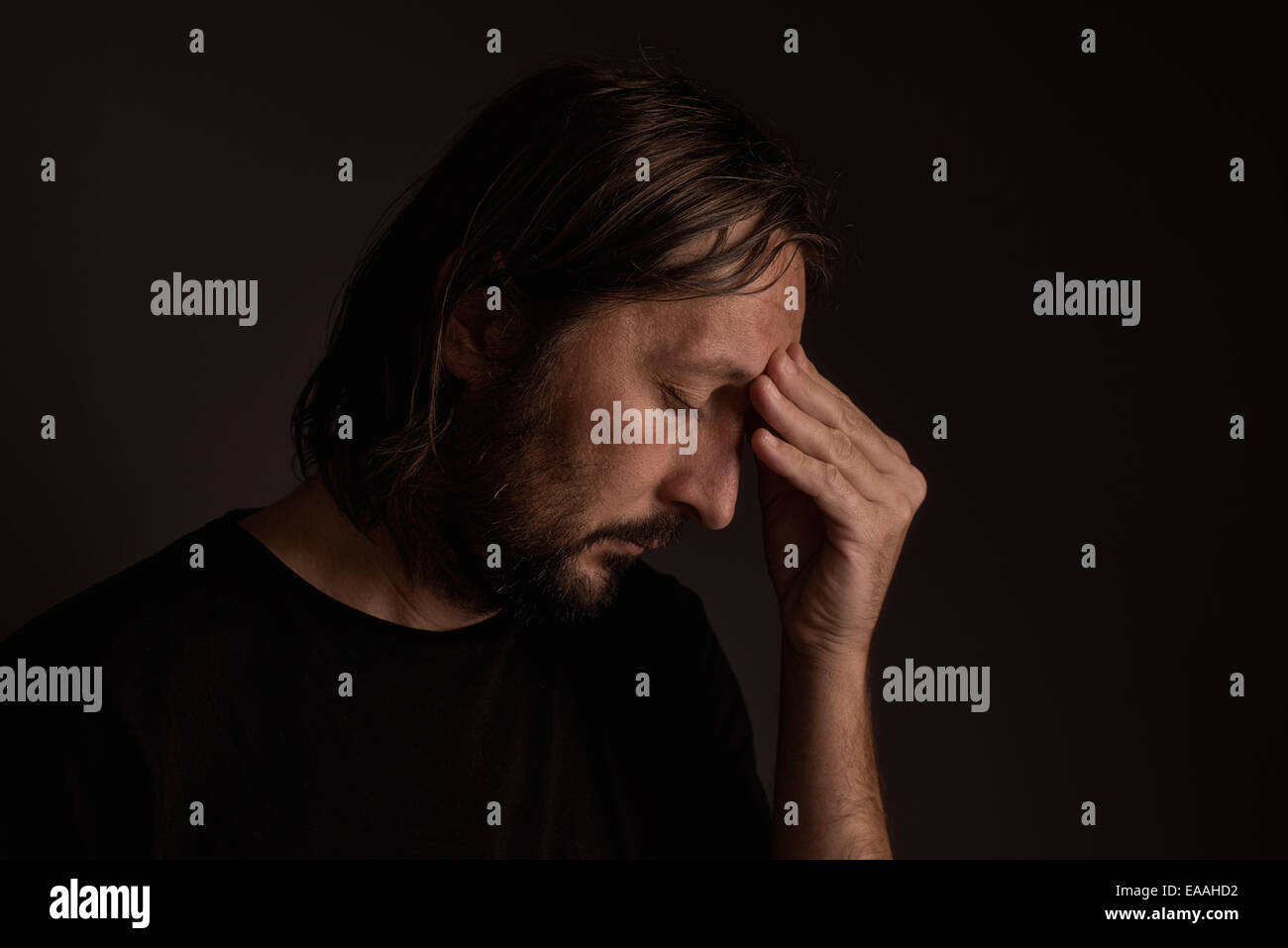 Bearded adult man with migraine headache, low key portrait Stock Photo