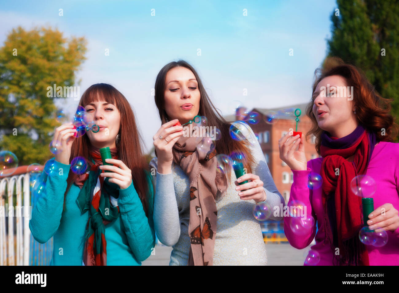 Three young beautiful women blow bubbles Stock Photo