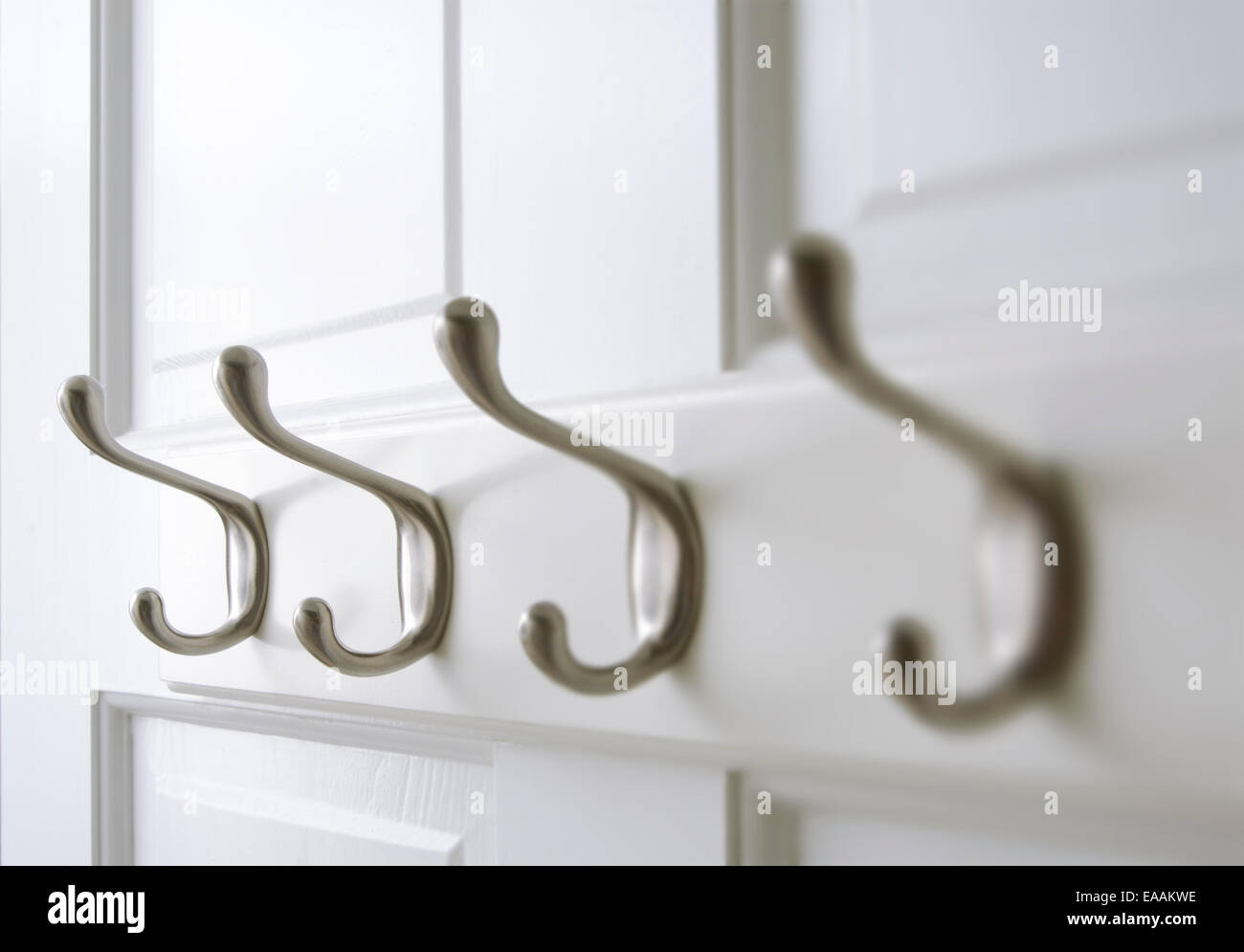 Chrome coat hooks are mounted on the back of a closet door. Stock Photo