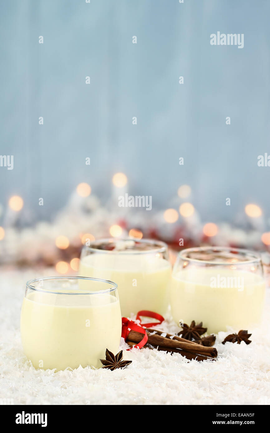 Three glasses of fresh eggnog with cinnamon sticks and star of anise ready for the Christmas season with copy space. Extreme sha Stock Photo