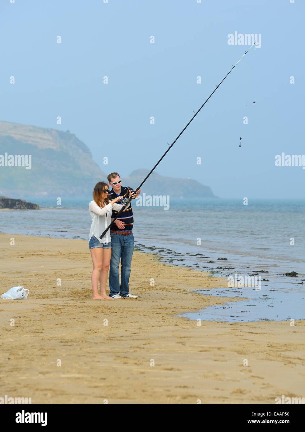 A young couple learning to fish on the beach in Padstow Cornwall England uk Stock Photo