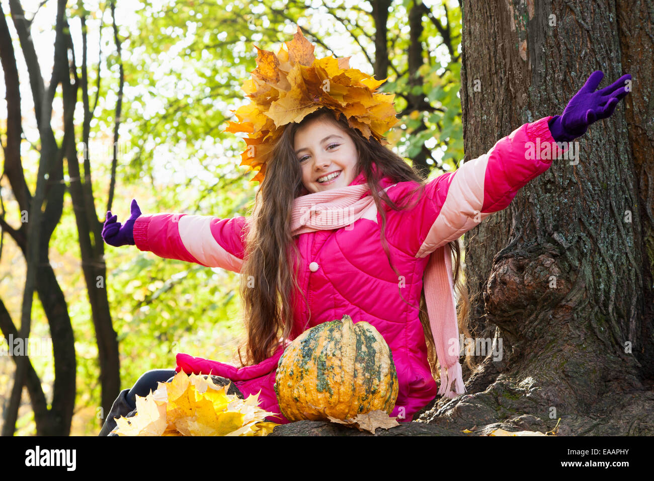 girl in a wreath of maple leaves with pumpkin in autumn park Stock ...
