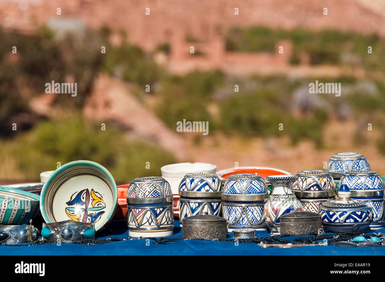 Horizontal close up of traditional Moroccan handicrafts on the roadside with Ait Benhaddou kasbah in the background. Stock Photo