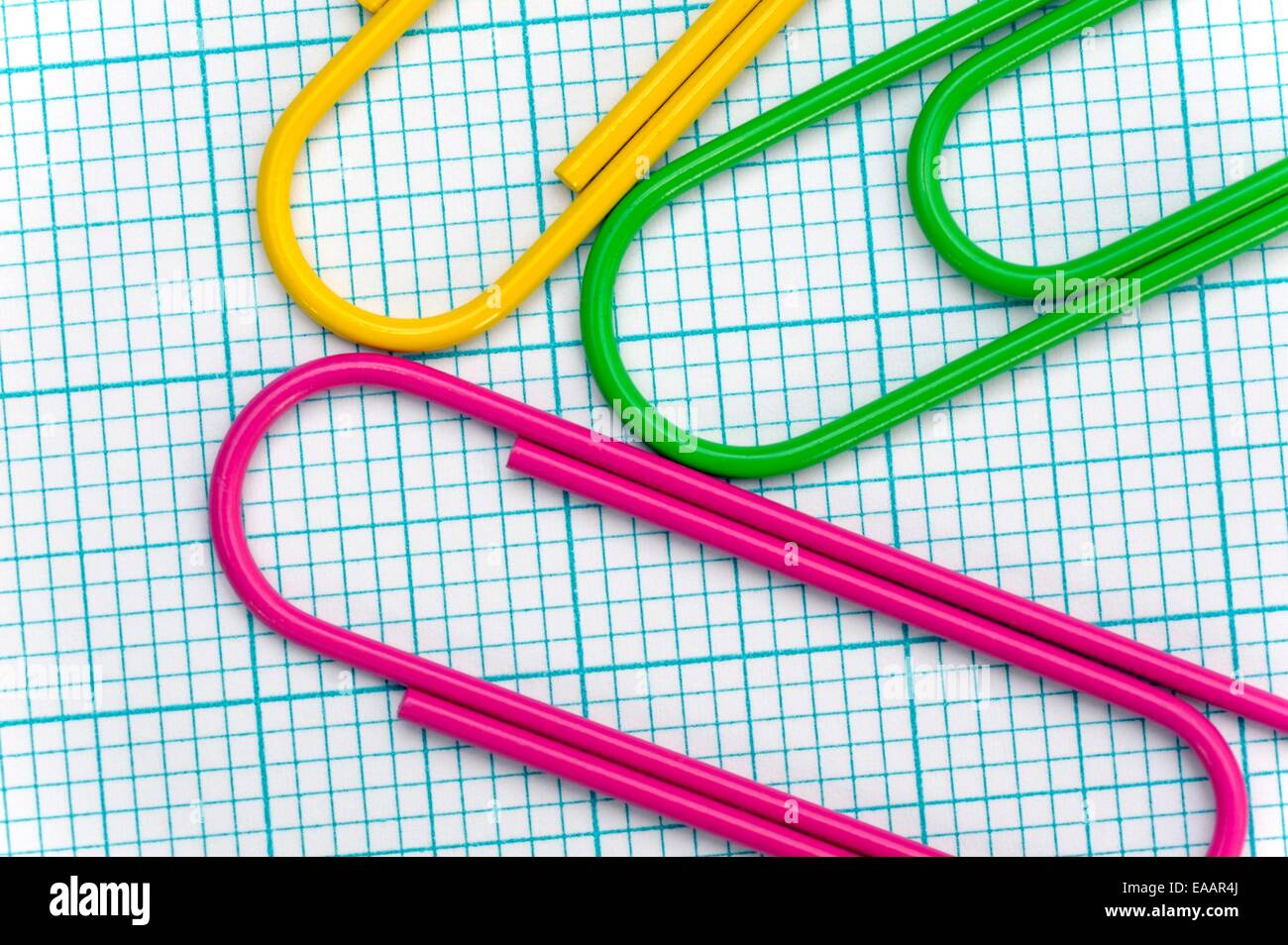 Giant paper clips arranged on a graph paper background Stock Photo