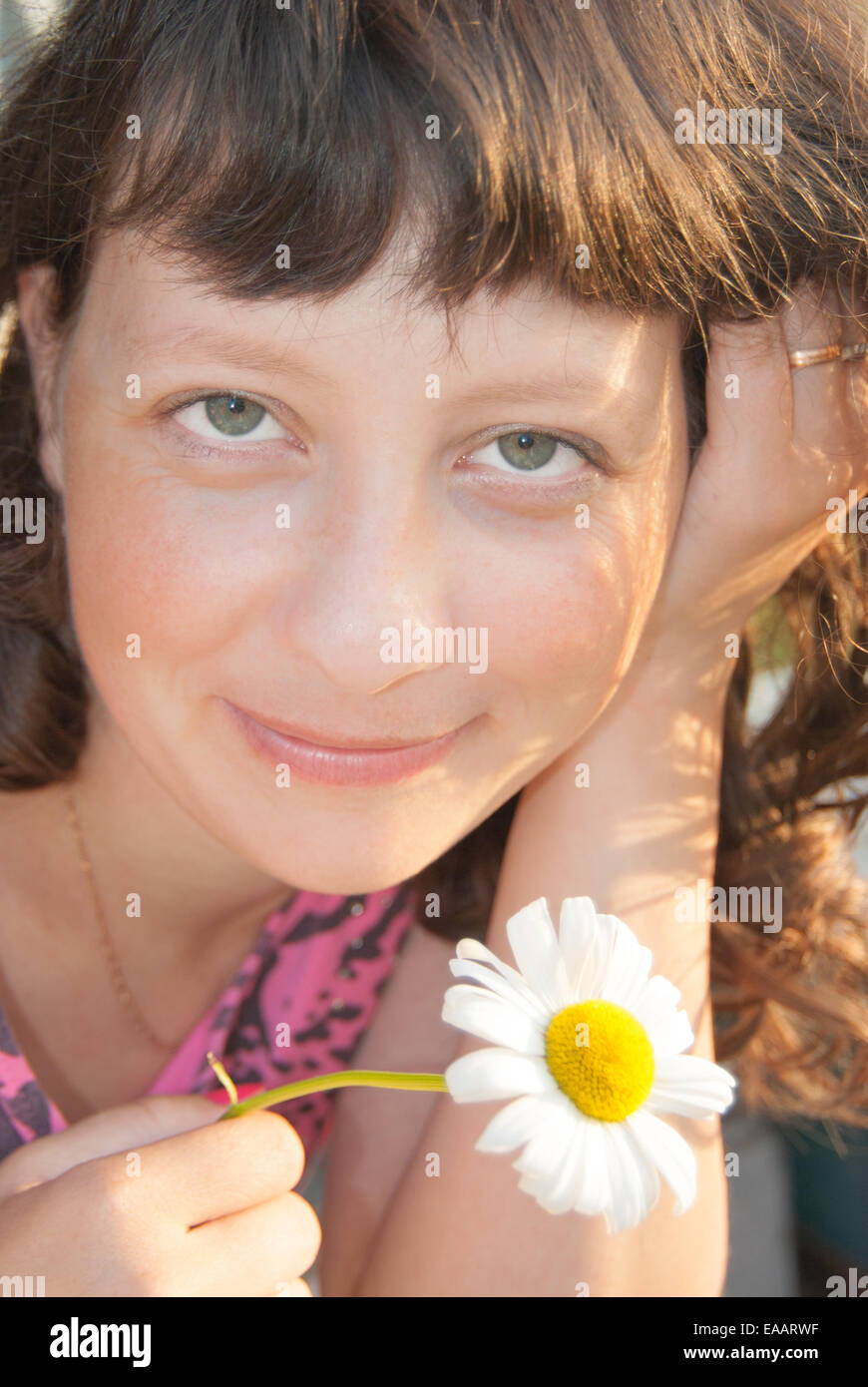 A young, smiling girl with a white flower Stock Photo - Alamy