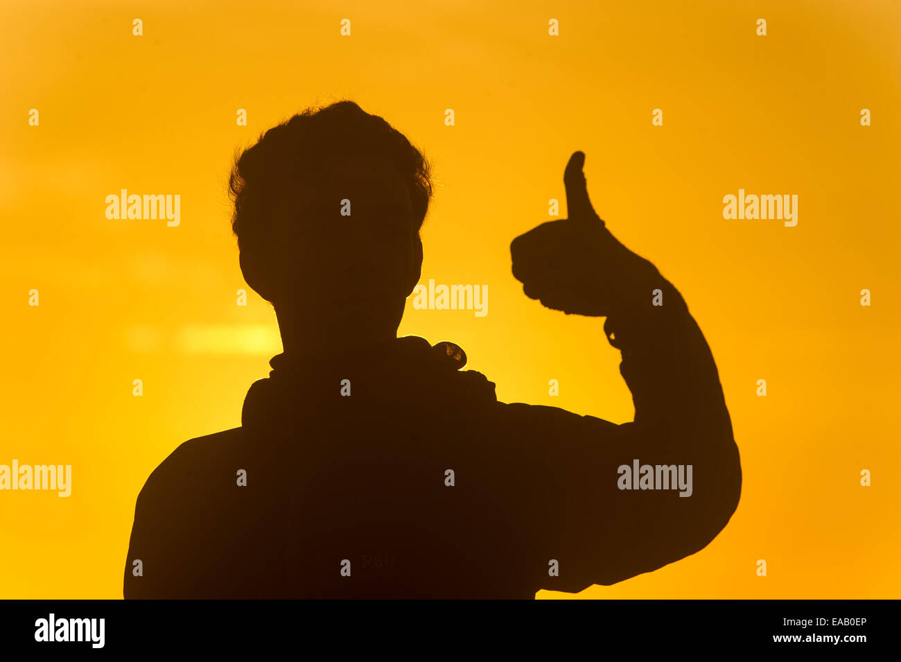 Silhouette of a man at sunrise giving a thumbs up sign. Stock Photo