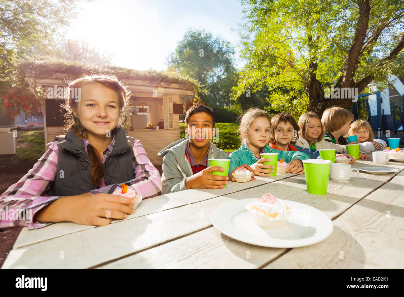 Many children sit at table with bright cups Stock Photo