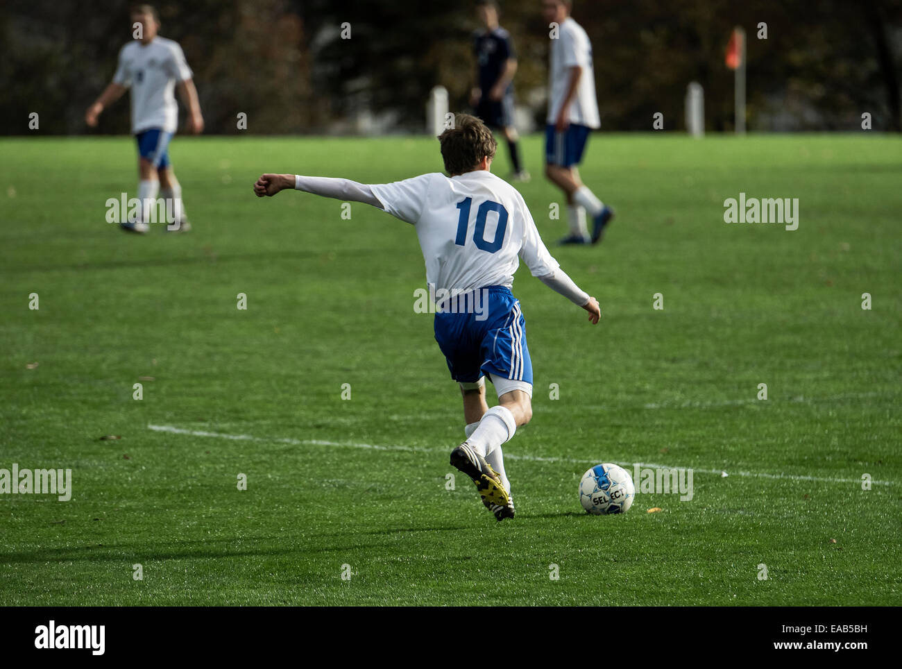 Youth soccer player takes a free kick during a match game. Stock Photo