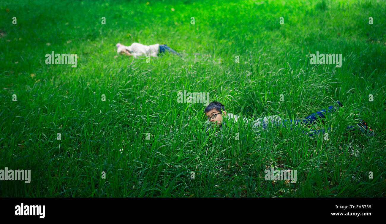 Hiding in the long grass. Boy and girl pay in meadow. Stock Photo