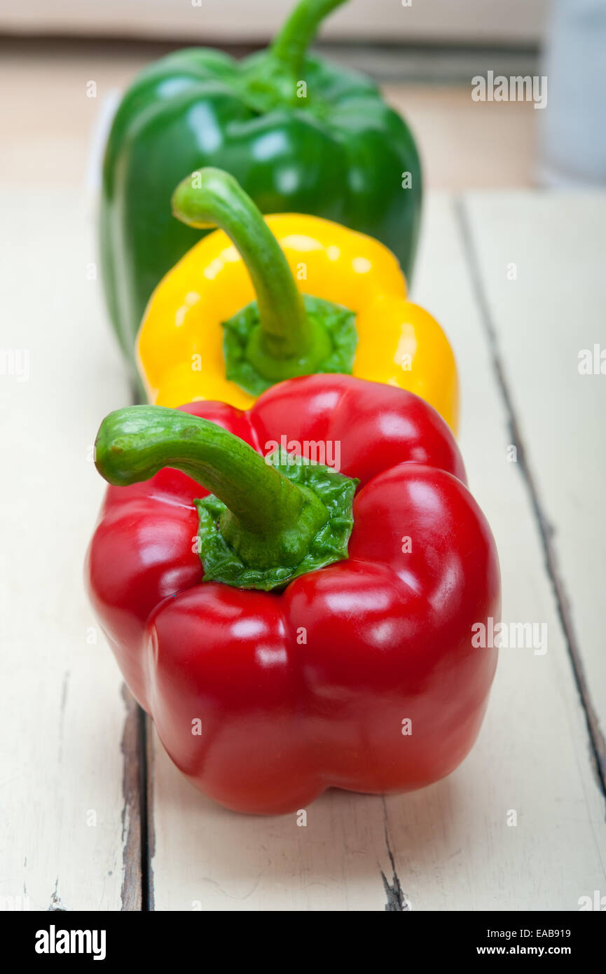 three fresh bell peppers over old wood table Stock Photo - Alamy