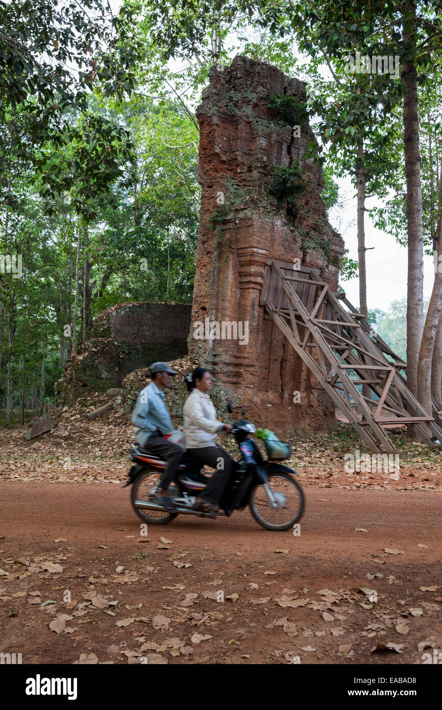 Cambodia.  Bakong.  Couple on a Motorbike Passing Tower Braced against Falling. Stock Photo