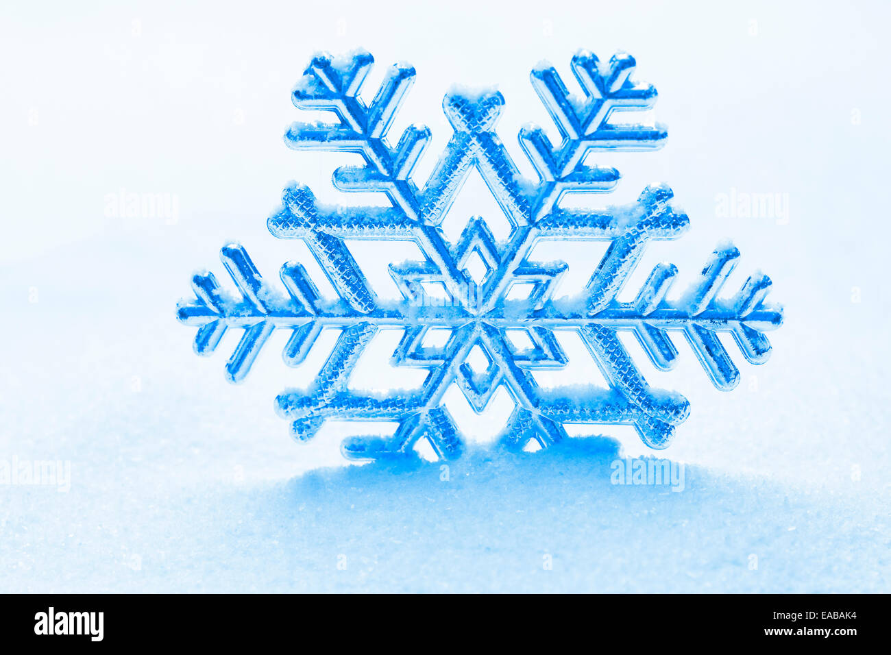 snowflake ornament against a background of snow Stock Photo