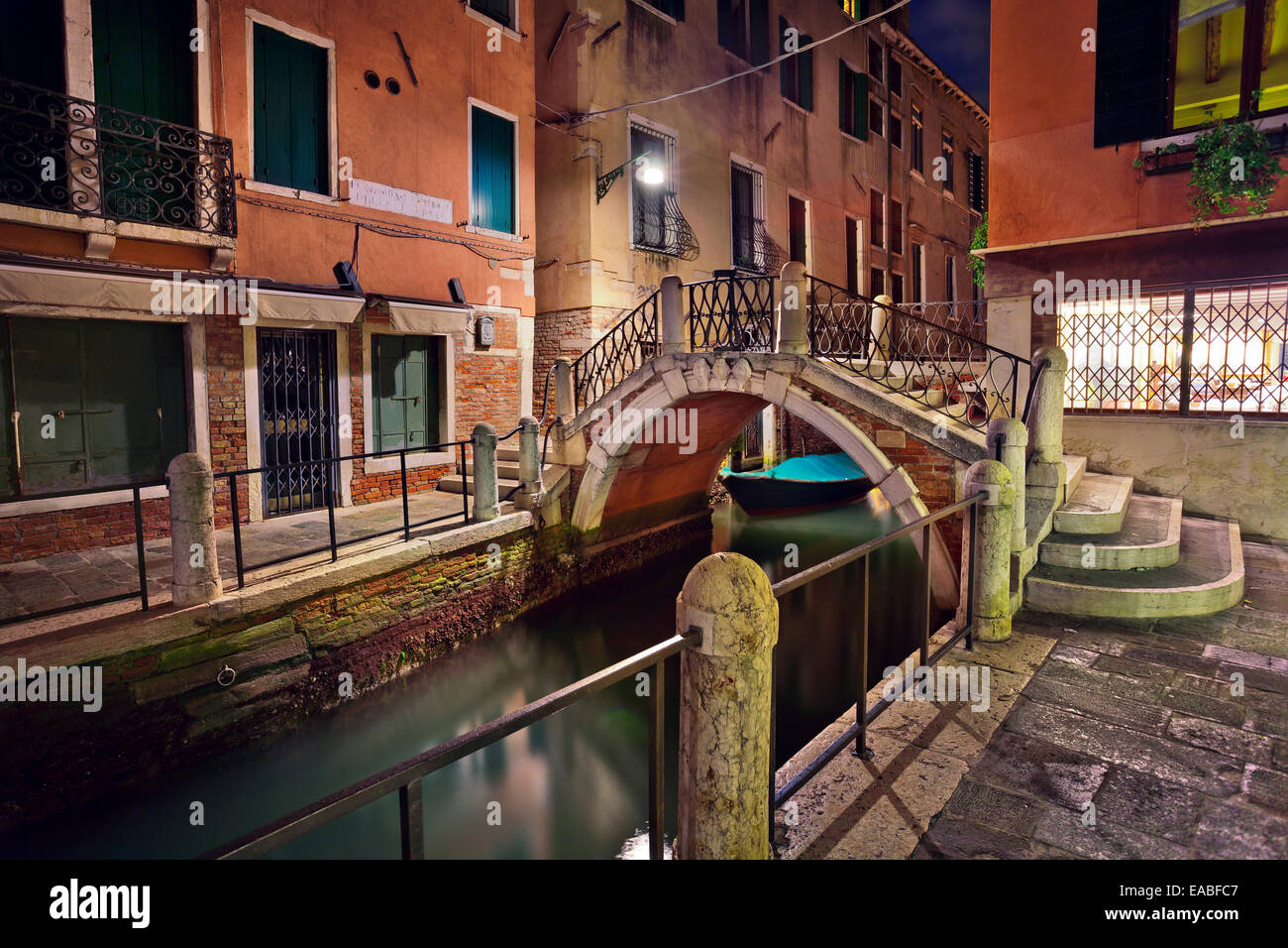 Image of one of many canals with arch bridge in Venice at night Stock
