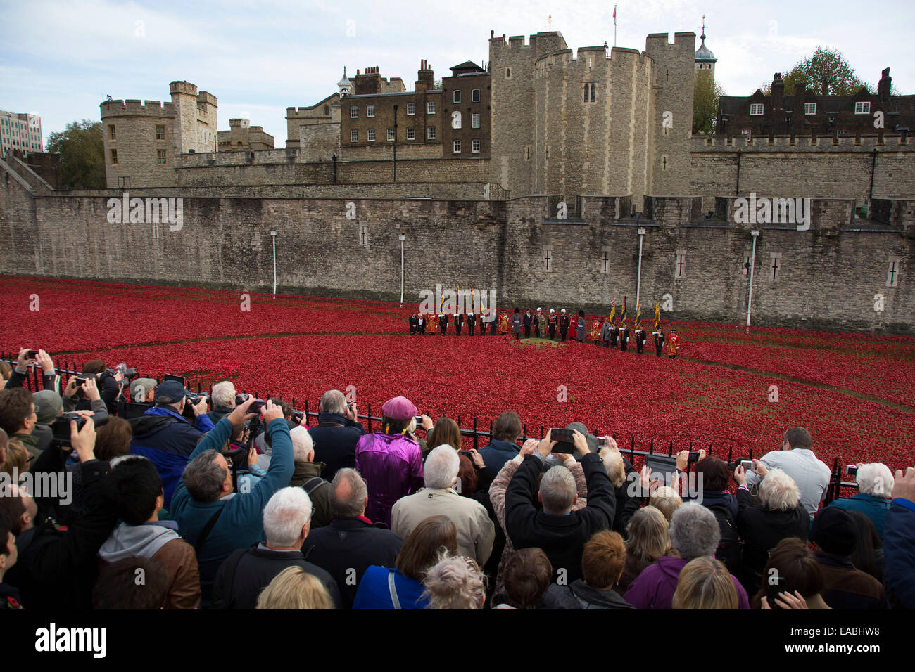 London, UK. 11th November, 2014. Crowds gather on Armistice Day to see the final poppy planted at the Tower of London, and to join in a two minute silence. 888,246 ceramic remebrance poppies have been planted. One for each life lost in the First World War. The installation has been made by Created by ceramic artist Paul Cummins, with setting by stage designer Tom Piper, and thousands of volunteers. Credit:  Michael Kemp/Alamy Live News Stock Photo