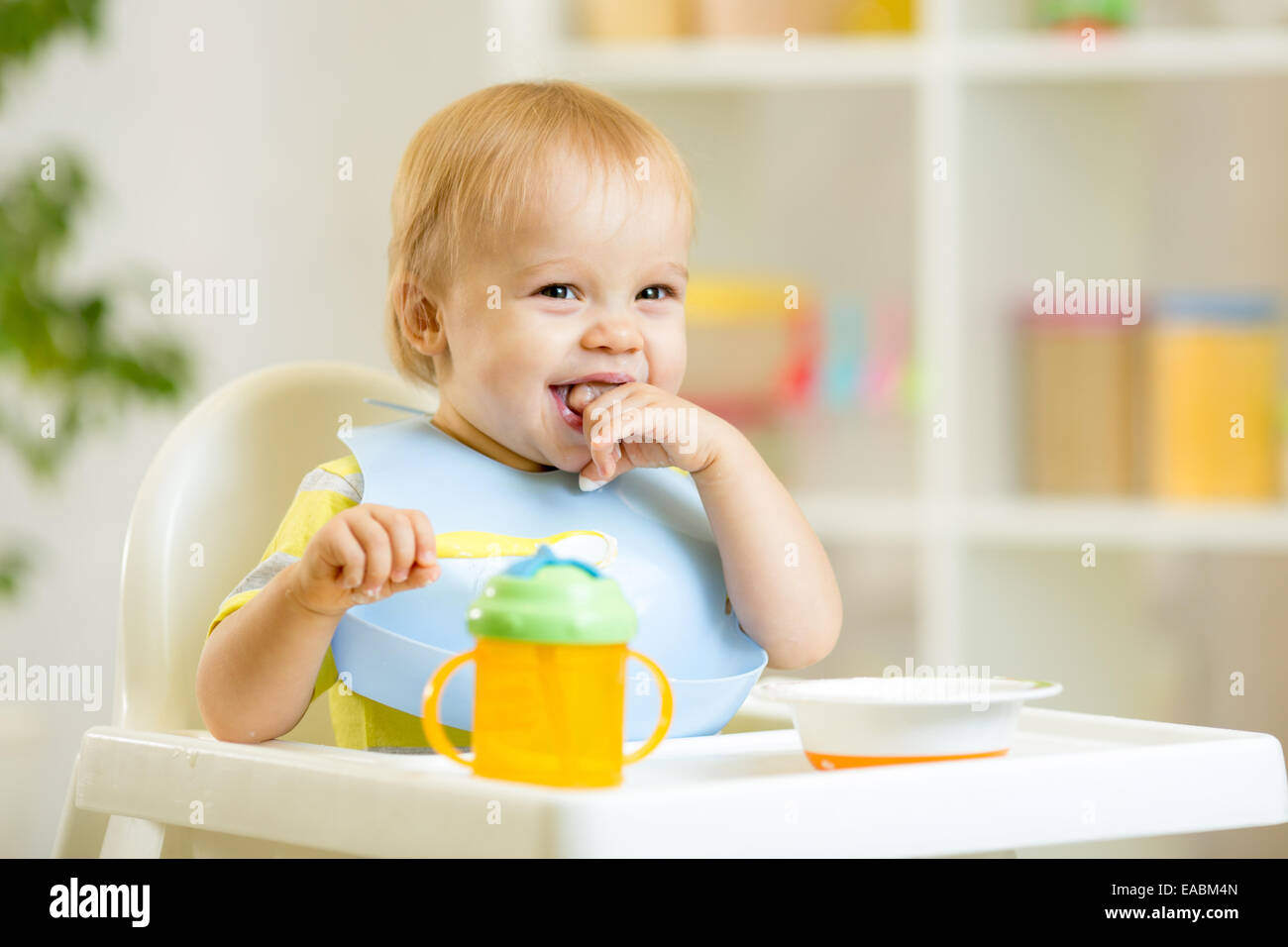 happy baby kid boy eating itself with spoon Stock Photo