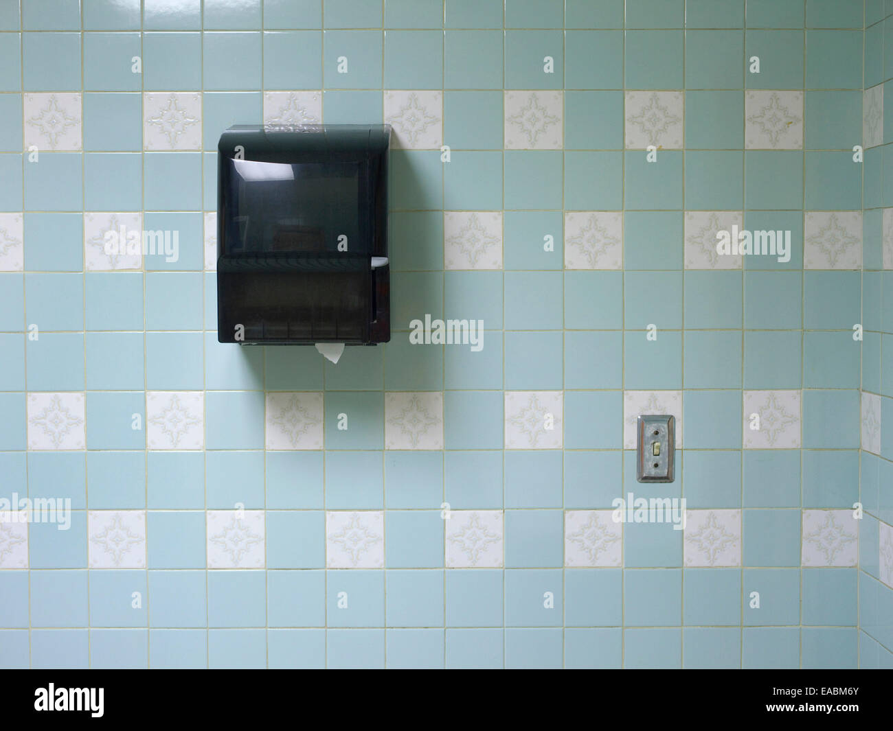Paper towel dispenser and blue ceramic tiles of public men's room Stock Photo
