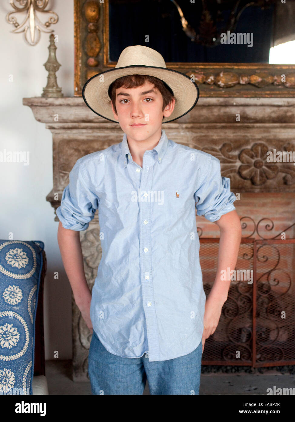 Portrait of Young boy wearing straw hat in Mexican style room with fireplace. Stock Photo