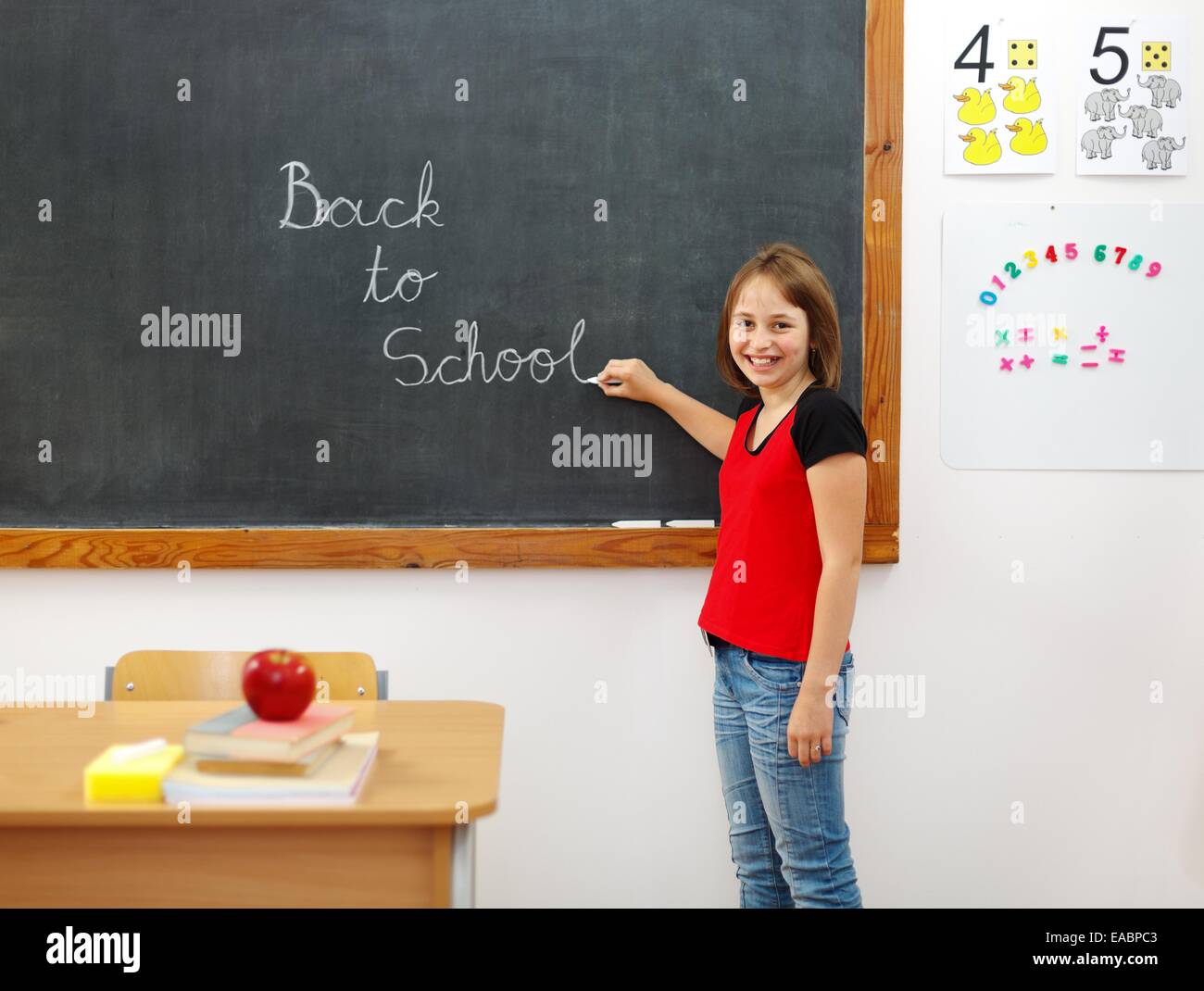 Elementary school girl writing Back to School on chalkboard Stock Photo ...