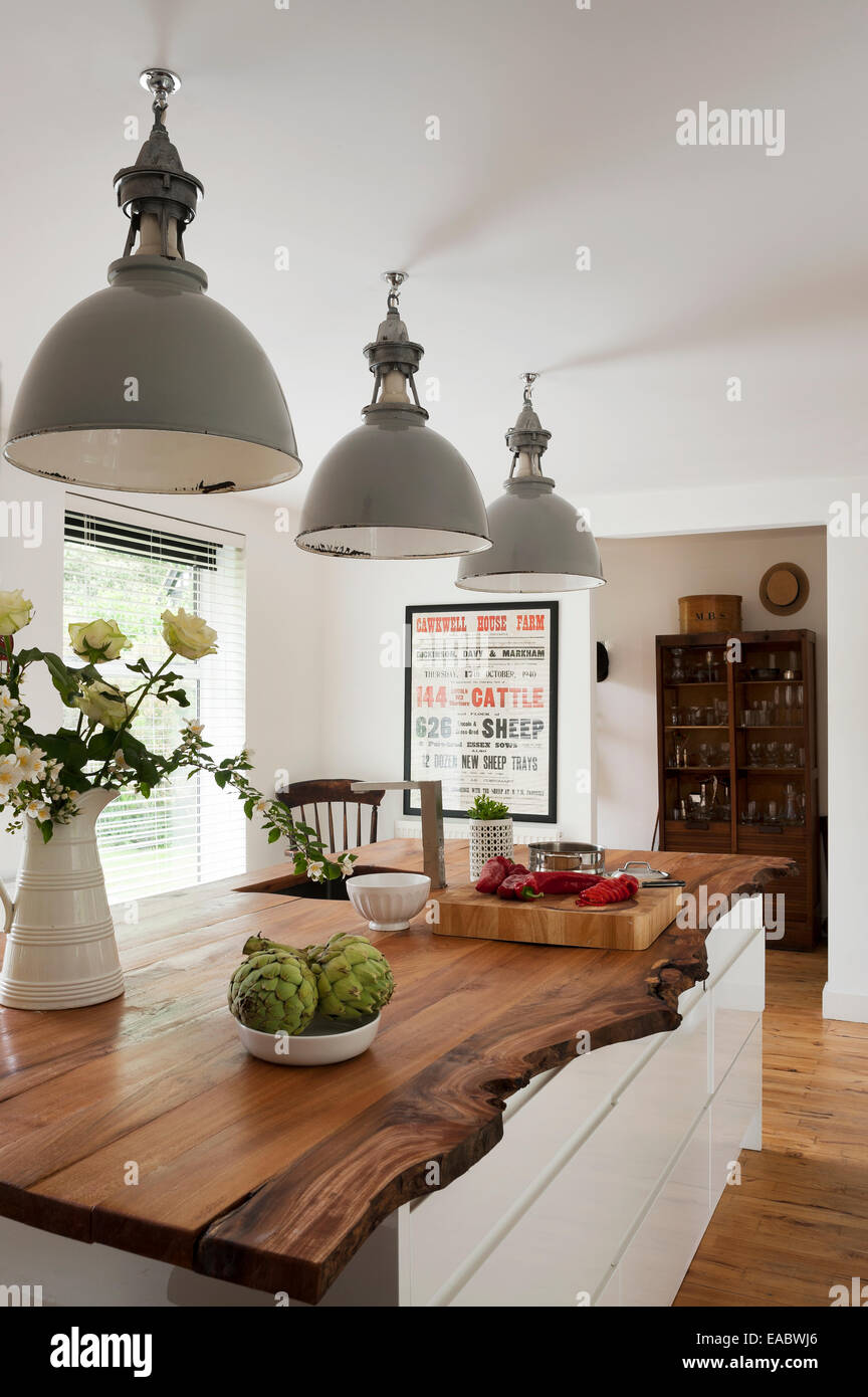 Three industrial lamps above elm-topped kitchen island unit Stock Photo