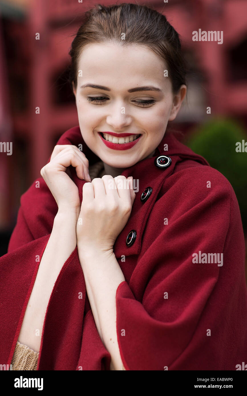 Portrait of smiling young woman wearing red cape Stock Photo Alamy