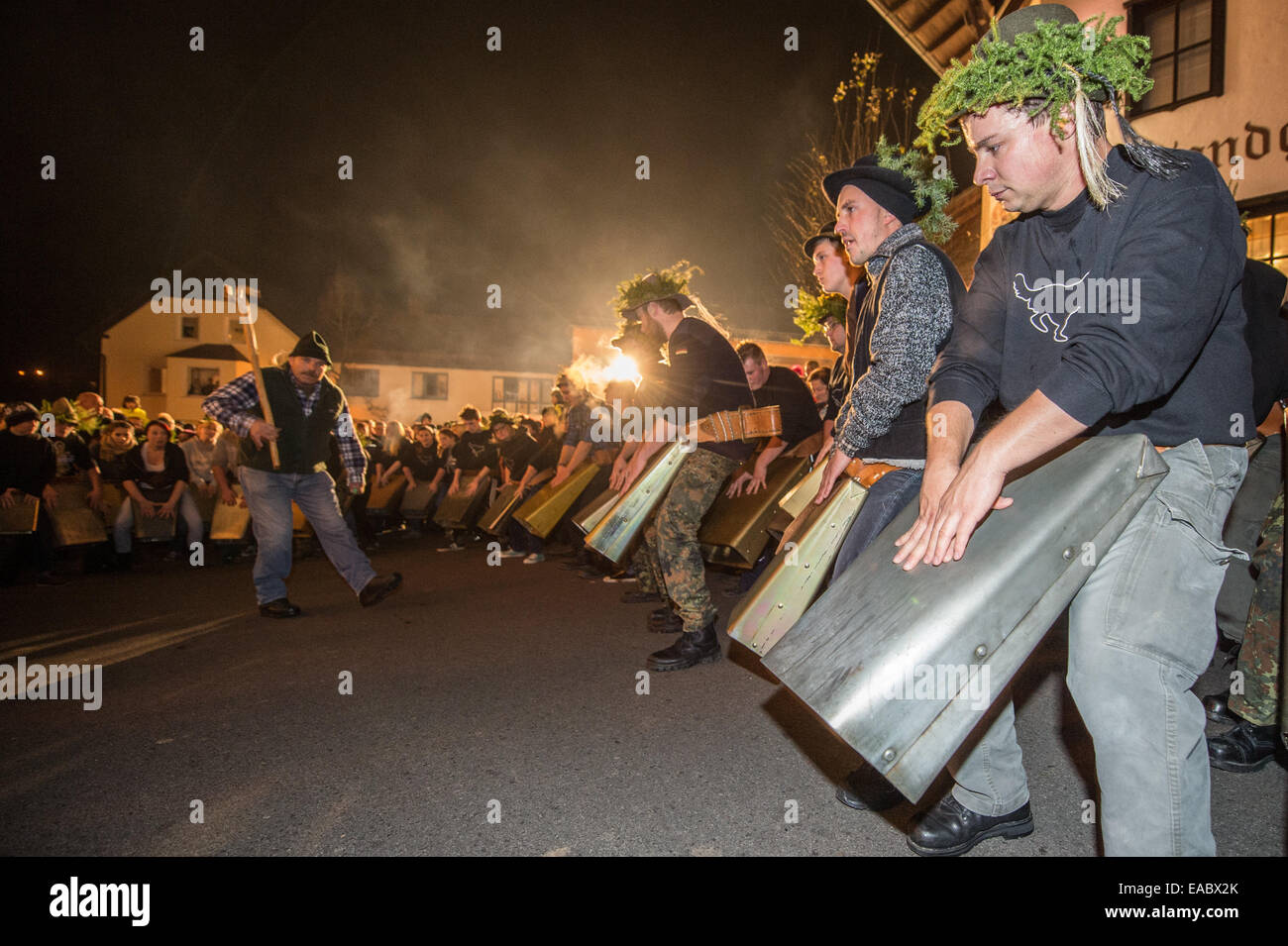 Participants in the 'Wolfsauslassen' (a local custom in the Bavarian Forest) ring large cow bells in Rinchnach, Bavaria, 10 November 2014. Around 600 boys and some girls come together every year for 'Wolfsauslassen.' According to old customs, the threatening sound of the bell chimes is meant to scare away wild animals. Photo: Armin Weigel/dpa Stock Photo